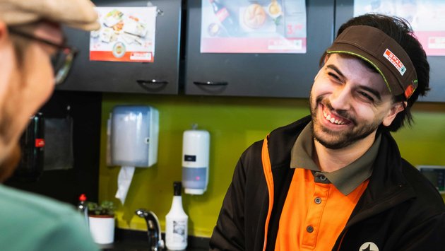 Smiling Turmöl shop employee serving a customer at the counter.